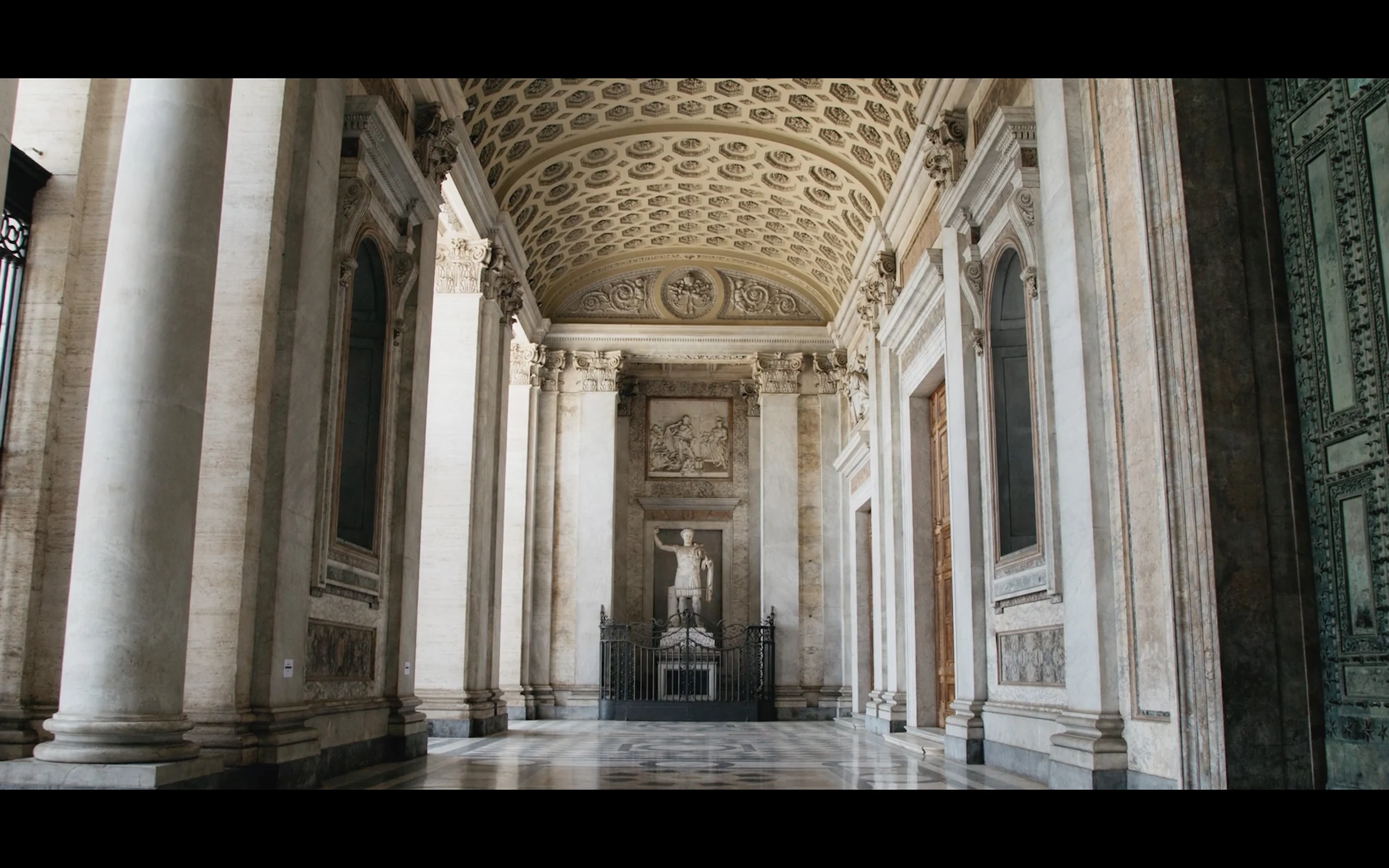A vaulted, frescoed corridor in Rome receding into shadow