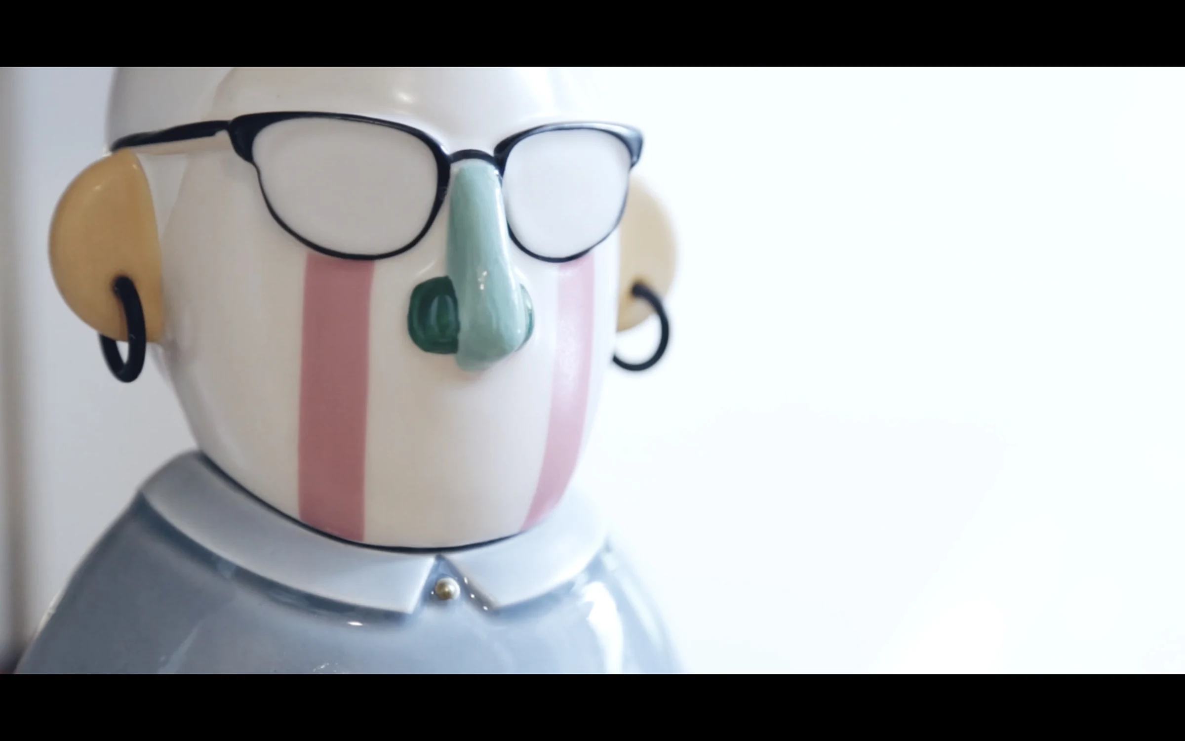 A ceramic bust wearing oversized glasses, its face split into color blocks