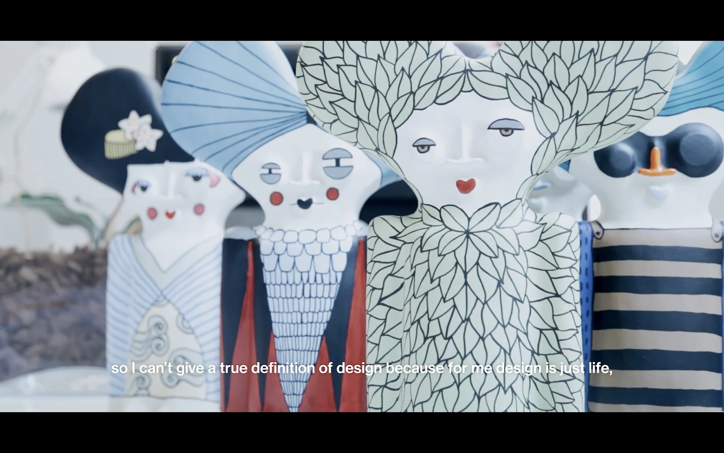 An illustrated textile pattern of stylised faces, foliage, and folk motifs