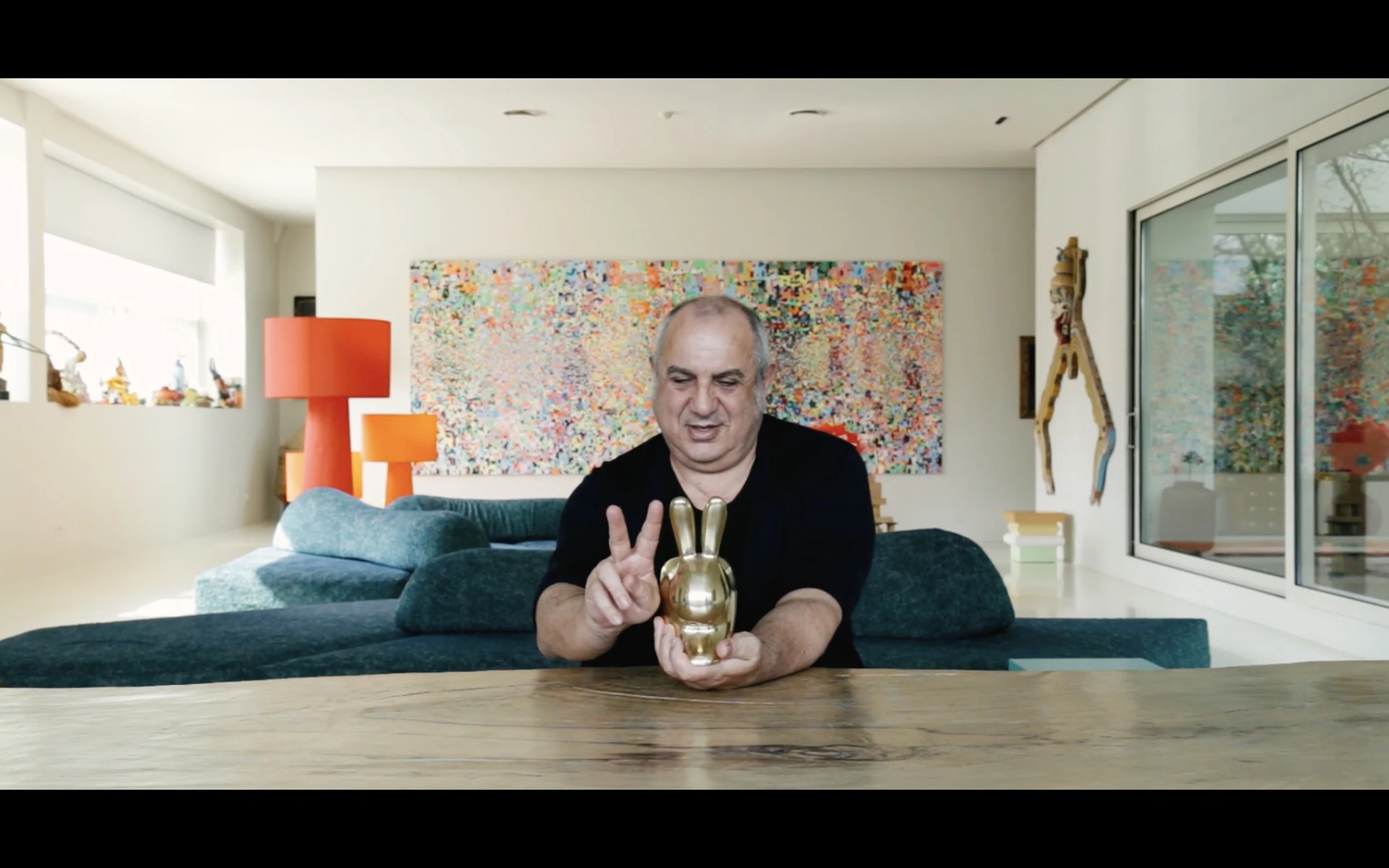 A designer seated in a living room holding a small golden object