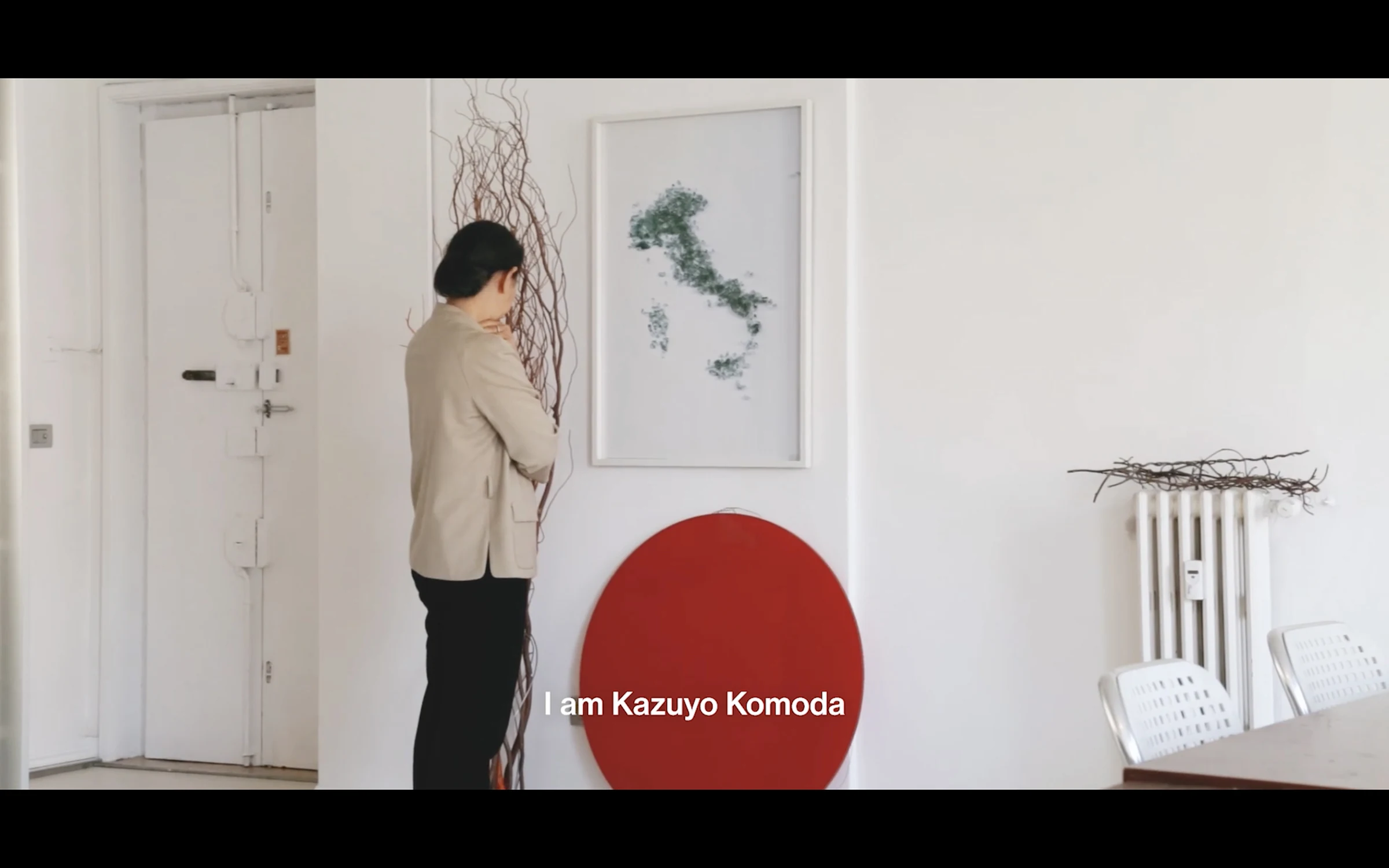 A visitor viewing a map of Italy and a red disc mounted on a gallery wall